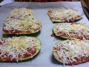Sliced zucchini topped with tomato sauce and shredded cheese ready to be cooked in the oven!