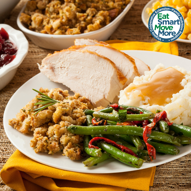 Thanksgiving plate of turkey, mashed potatoes with gravy, stuffing, and green beans with red peppers, surrounded by dishes of cranberry sauce, stuffing, and corn