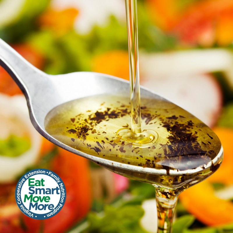 oil used to make salad dressing drizzling over spoon atop a plate of salad