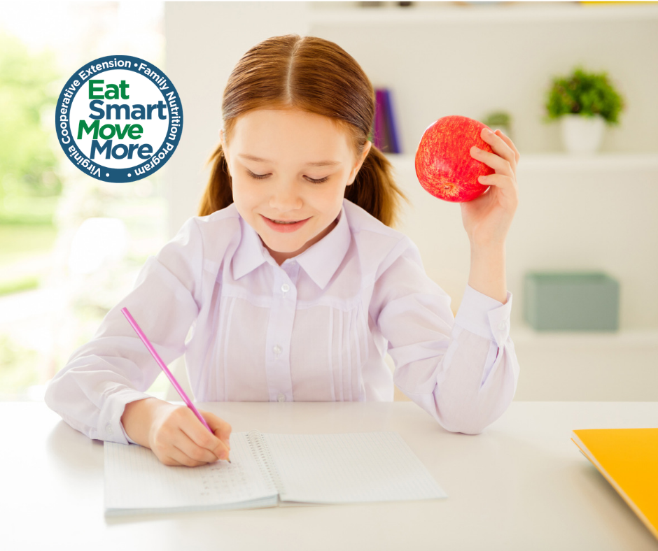 young girl eating apple while doing homework