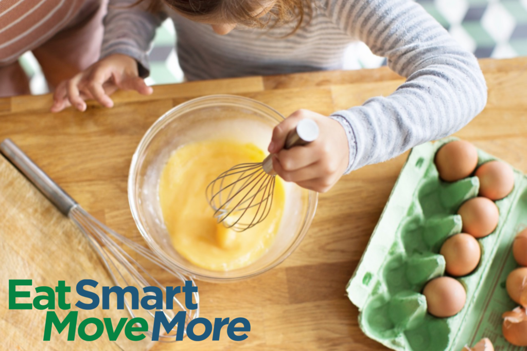 Young girl whisking eggs in bowl, with egg carton open and the Eat Smart Move More logo.