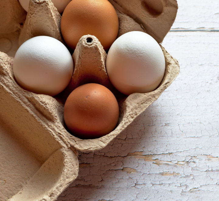 White and brown eggs in a brown egg carton.